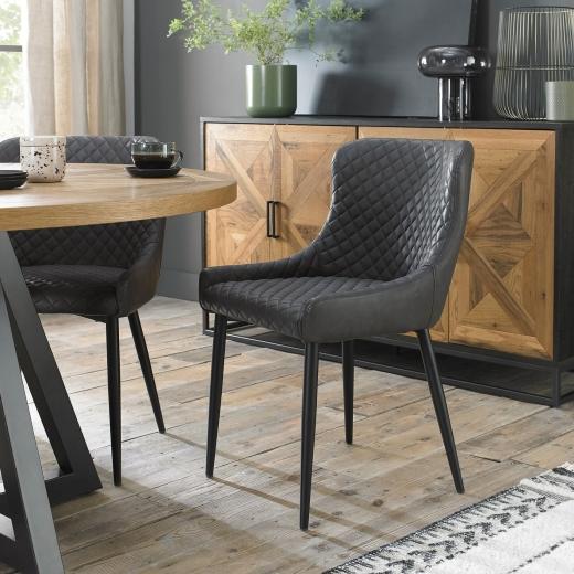 The Cezanne Chairs in dark grey faux leather bring a sleek, modern touch to the warm, rustic vibe of...